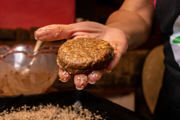 a mão de uma cozinheira mostrando um biscoito de banana e castanha de caju com a massa ainda crua, pronta para ir ao forno