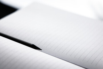 Black pencil put on the blank white paper notebook (diary) between two sheet page. Book with line for taking note, memo and idea write down concept.