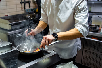 man chef cooking fried salmon fish in frying pan on kitchen