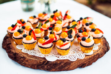 delicious cupcakes with cream and fruit on a wooden table