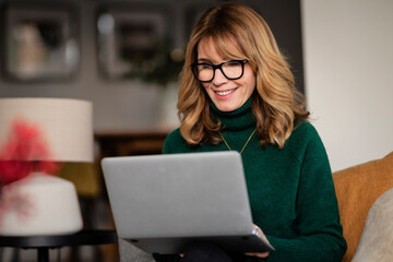 Casual woman sitting at home and using laptop for work