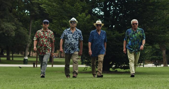 Cool-Looking Senior Men in Sunglasses and Colorful Hawaiian Shirts Walking Confidently Towards the Camera in Slow Motion. They Fist-bump. Serious Elderly Males Fighting Stereotypes and Ageism 
