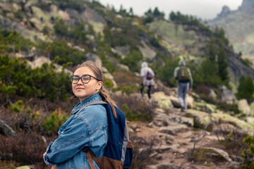 Naklejka na ściany i meble young woman is hiking with friends on mountain