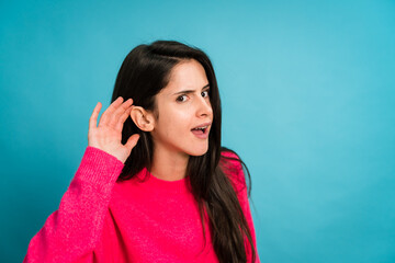 Young woman touching ear and looking at camera pretending to listening