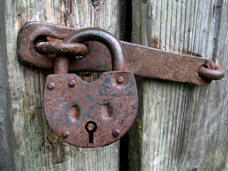 rusty padlock on the wooden door of an old barn