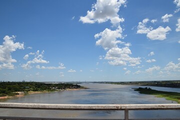 river view from a bridge with blue sky and city skyline in the horizon