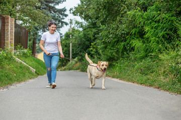 Naklejka na ściany i meble Happy young woman jogging with labrador dog. Playing pets, pet concept.
