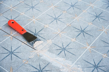 Grouting ceramic tiles. Tilers filling the space between tiles using a Stainless steel trowel.