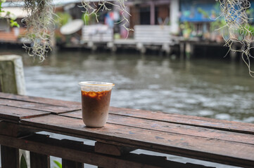 Cup of coffee on the wooden table beside the river.in the city local area thailand