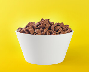 Chocolate cereals in white bowl. Chocolate flavored corn flakes. Wheat. Cocoa. Crispy. Crunchy. Breakfast. Snack. Granola. Oat.