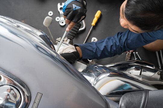 People are repairing a motorcycle Use a wrench and a screwdriver to work