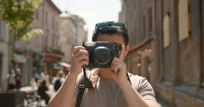 Male photographer taking photos of an old town with digital camera