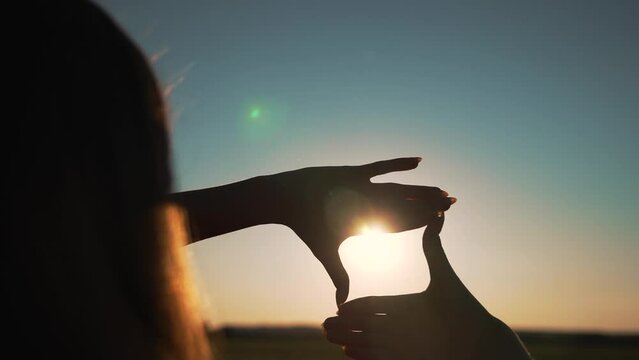 Business strategy. Girl folded her hands in frame at sunset. Silhouette of girl in natural park. Fingers at sunset. Work planning. Girl in field folded her hands into frame. Business planning concept.