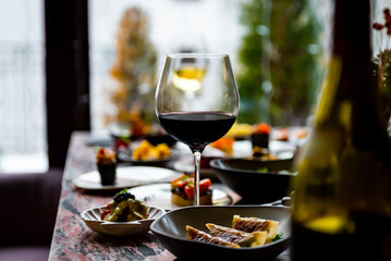 glass with red wine and wine snack set, food from spain, cheese, meat, vegetables and other appetizers on table