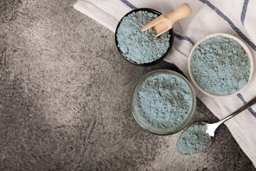 Blue spirulina powder in bowls and spoon on black marble background. Natural vegan superfood. food...