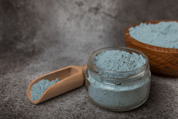 Blue spirulina powder in bowls and spoon on black marble background. Natural vegan superfood. food supplement. place for text. Copy space.
