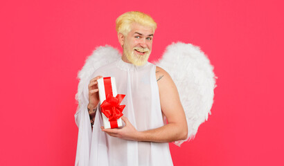 Valentines day angel. Smiling bearded man in white wings with Valentine gift box. Present with love.