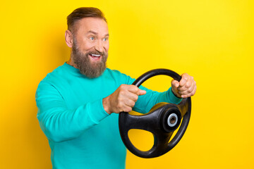 Photo portrait of nice retired man driving fast car steering wheel banner wear trendy aquamarine outfit isolated on yellow color background