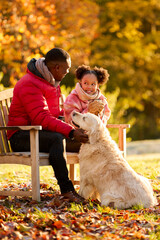 Fototapeta premium Father And Daughter With Hot Drink Sitting On Bench With Pet Dog On Walk In Autumn Countryside