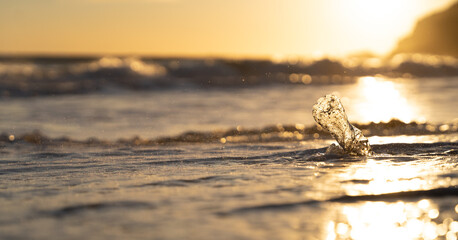 close up of a plastic bottle on the shore of the beach. Plastics dragged by the sea. Sunset light. Copy space to the left