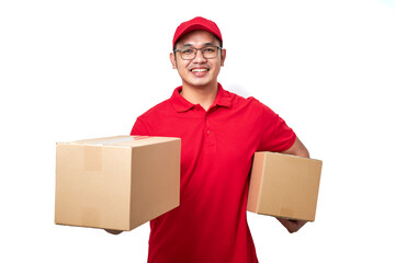 Smiling asian courier man wearing red uniform holding two boxes with orders, packing shipping items for clients.