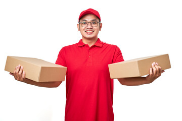 Smiling asian courier man wearing red uniform holding two boxes with orders, packing shipping items for clients.