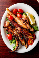 Grilled octopus. Prepared in traditional Italian style: fried in olive  oil, garlic and seasoned with salt and pepper. Served over bed of arugula salad, cherry tomatoes and seasoned with fresh herbs.