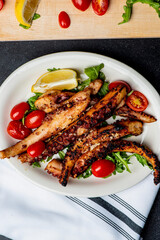 Grilled octopus. Prepared in traditional Italian style: fried in olive  oil, garlic and seasoned with salt and pepper. Served over bed of arugula salad, cherry tomatoes and seasoned with fresh herbs.