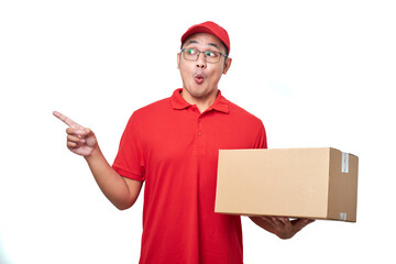 Young handsome asian delivery man holding delivery package shocked while pointing with hand and...