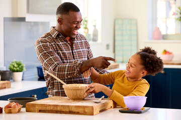 Family Shot With Father And Daughter Having Messy Fun Baking At Home In Kitchen