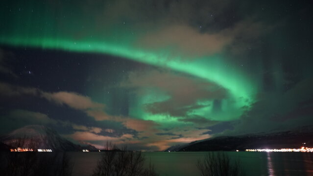 Northern lights (Aurora Borealis) with clouds reflecting light pollution. Norway, Tromso, Skibotn. © Petr
