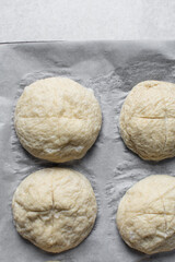 Boiled and scored pretzel buns dough on a baking sheet, German laugenbroetchen, boiled lye buns dough on a baking tray, process of making pretzel buns