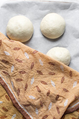 Bread bun dough that has doubled in size, dough that has risen, proofed dough on parchment lined baking sheet