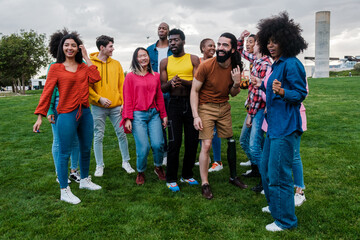 Group of young people from different cultures singing and dancing outdoors. Concept: lgtbi, pride, outdoors, lifestyle