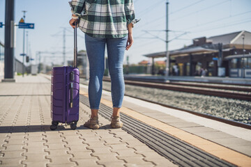 Fototapeta premium Woman with suitcase standing on train station. 