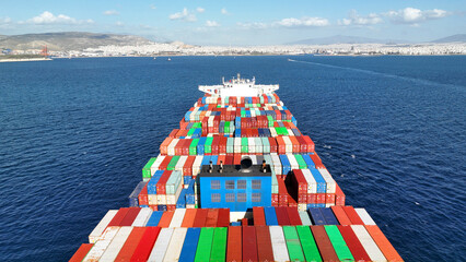 Aerial drone photo of truck size container cargo vessel cruising in deep blue sea near commercial port of Piraeus