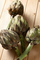 Raw artichokes on a wooden table, close-up