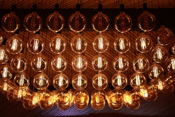 Stylish, modern and decorative lamps of Edison of round shape in the rows. Light bulbs in retro style. A lot celling glowing vintage LED lamps. Object for interior decoration, selective focus photo