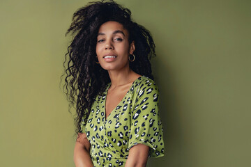 attractive black african american woman posing in stylish green dress isolated on green background