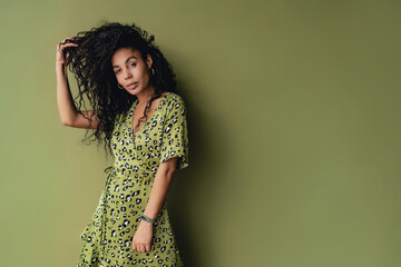 attractive black african american woman posing in stylish green dress isolated on green background