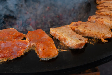 Process of cooking fresh juicy meat steaks on brazier at summer local food market - close up view. Outdoor cooking, gastronomy, cookery, street food and barbecue concept