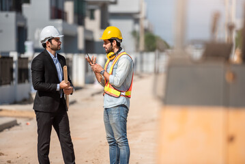 Professional civil engineer and architect in safety helmet hard hat working together in construction site, two men discuss about real estate project or production in industry