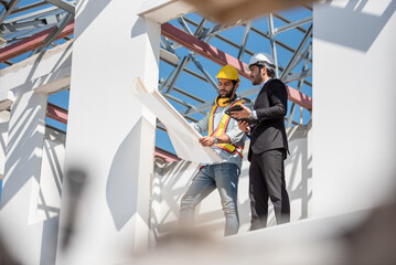 Teamwork men in construction site, Two civil engineer in safety helmet hard hat using digital...