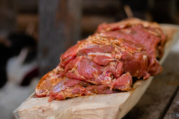 Freshly juicy marinated meat with spices and onion on wooden board at summer local food market - close up view. Outdoor cooking, gastronomy, cookery, street food concept