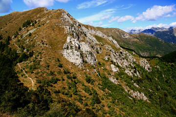 Obraz premium Panoramic view of the landscape with mountains and green hills in the foreground against a blue sky with clouds on Mount Cimetta, near Locarno in Switzerland