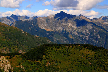 Naklejka na ściany i meble Panoramic view of the landscape with mountains and green hills in the foreground against a blue sky with clouds on Mount Cimetta, near Locarno in Switzerland