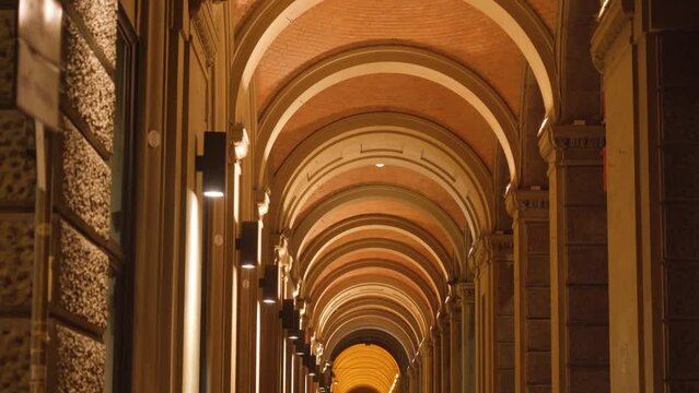 Ancient building medieval portico with big marble columns and high semi-circular ceiling illuminated with bright white light in evening in Bologna