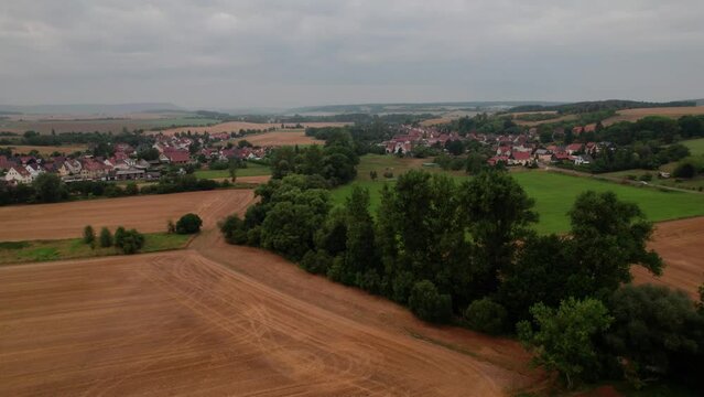 Aer ial view of a German village surrounded by meadows, farmland and forest in Germany.