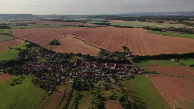 Aer ial view of a German village surrounded by meadows, farmland and forest in Germany.