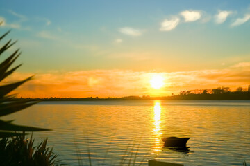 Obraz premium Small dinghy at anchor in silhouette back-lit by intense sunrise